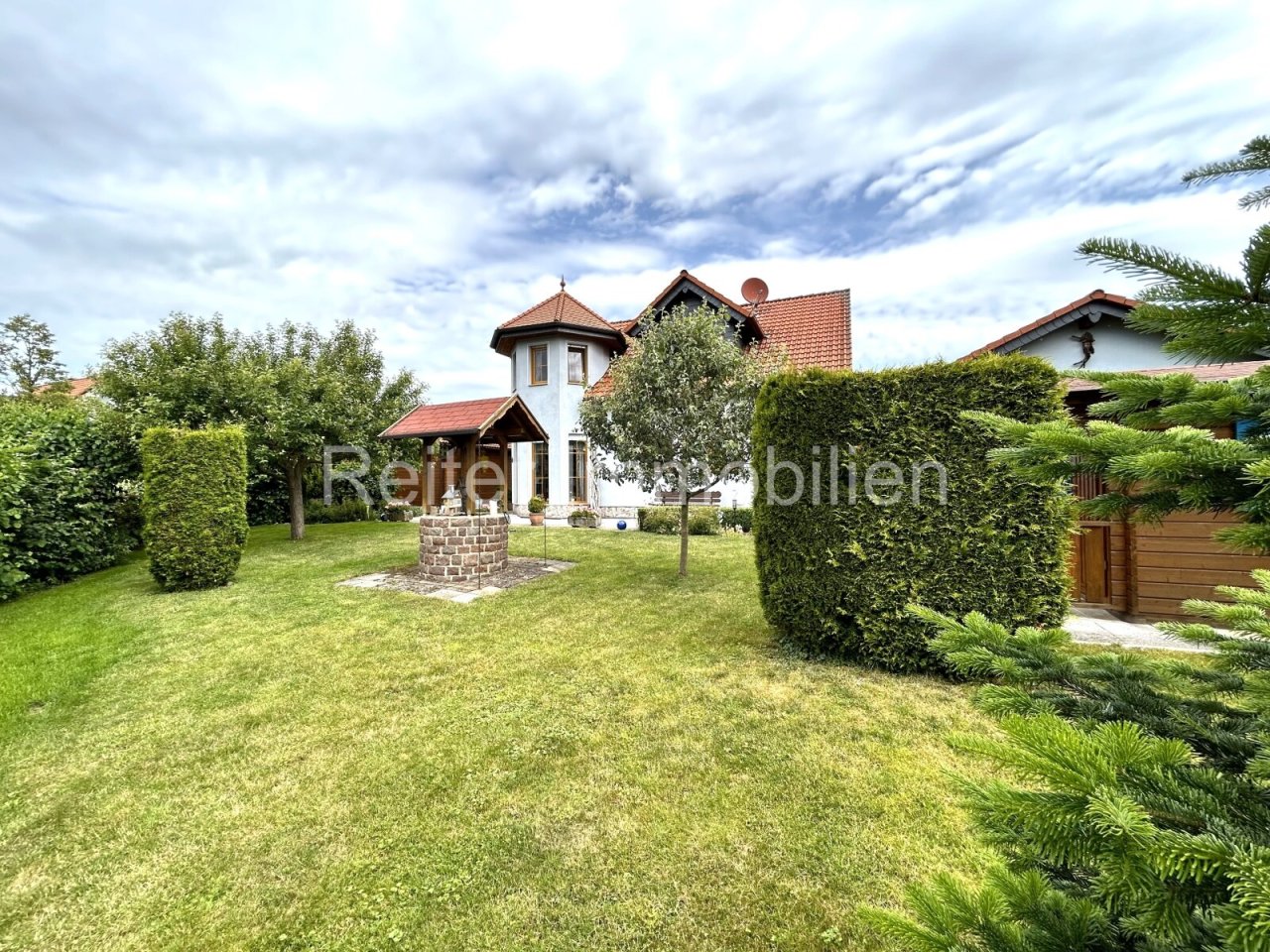 liebevoll gepflegter Garten mit Gartenhütte und Brunnen